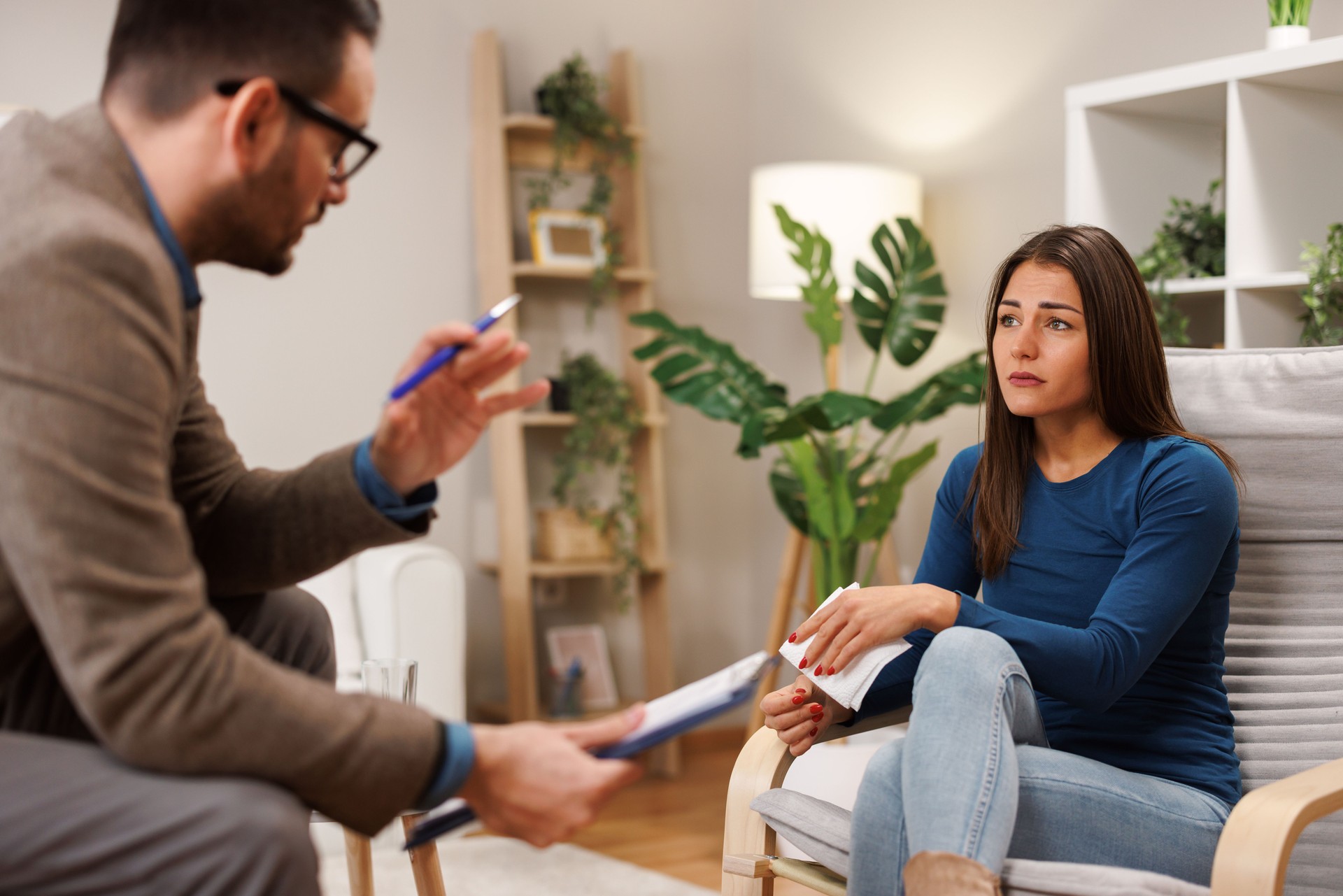 Psychologist talking with a sad patient during therapy session at home