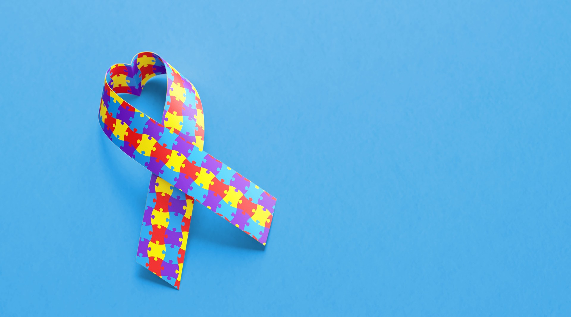 Heart Shaped Autism Awareness Ribbon On Blue Background